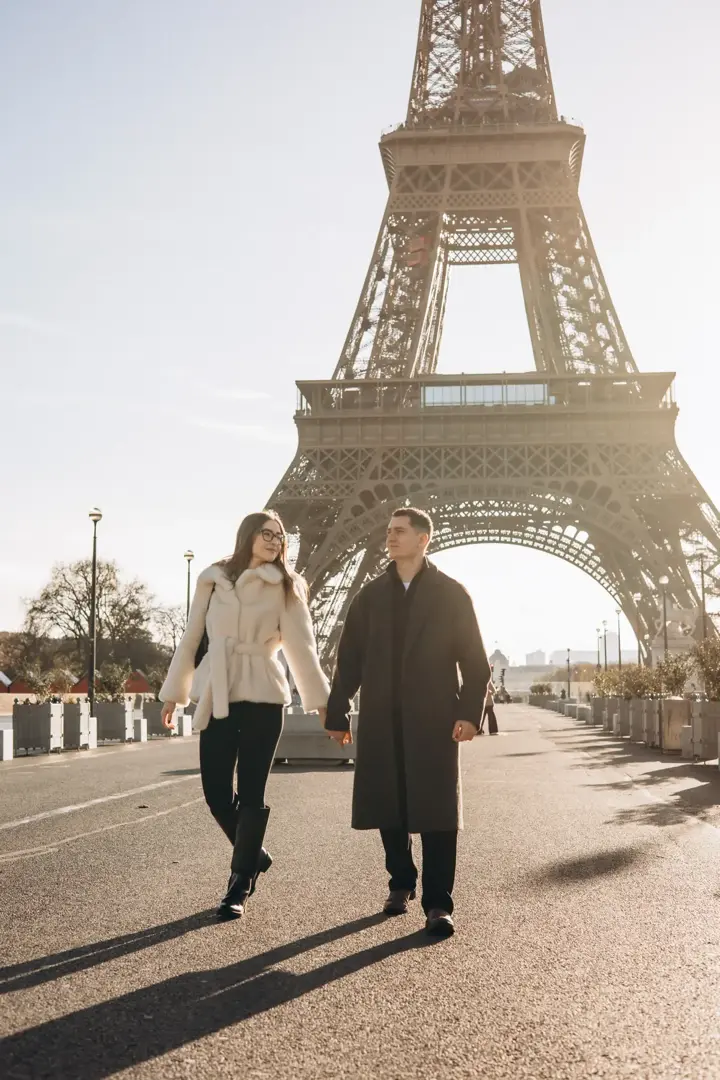 Couple walking hand in hand Eiffel Tower golden light Paris