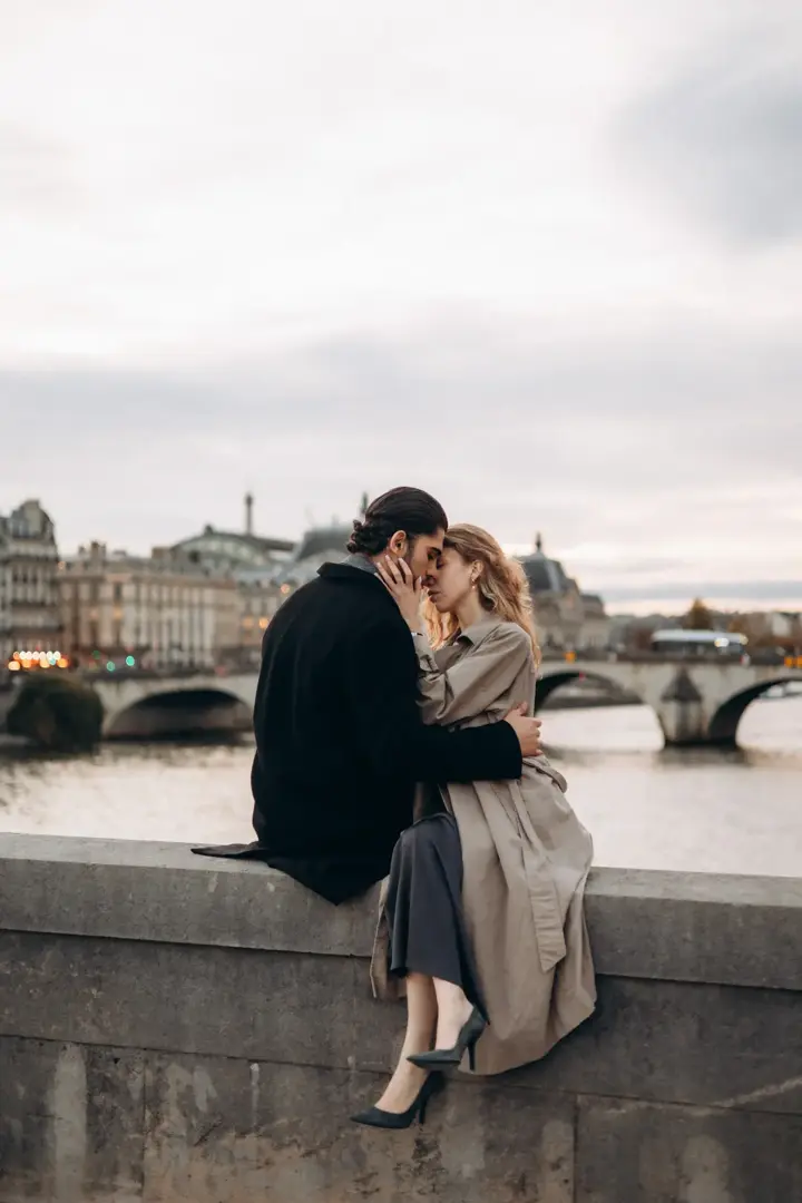 Couple sitting Seine river wall Paris romantic sunset