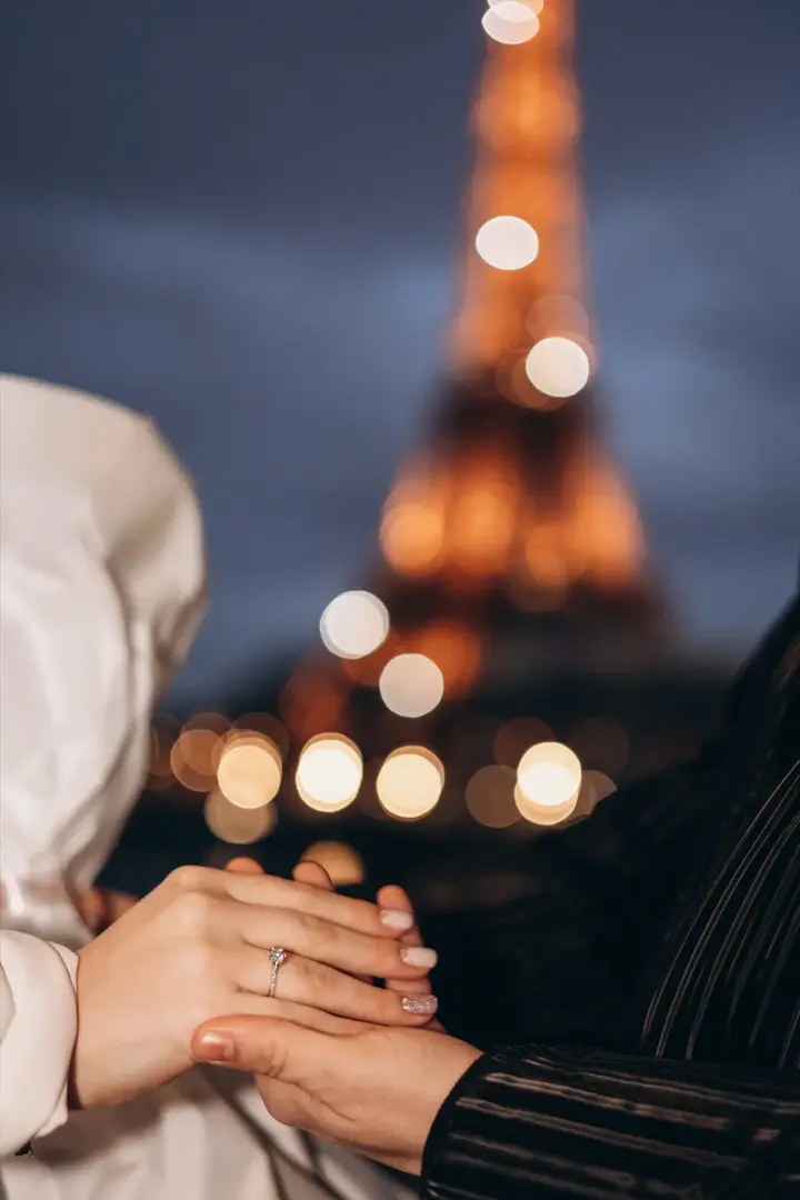 Hands with engagement ring bokeh Eiffel Tower night Paris